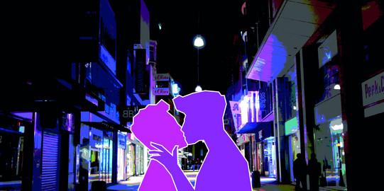 Two male figures kissing at night in the city centre of Dortmund