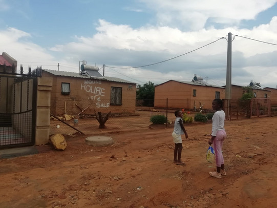 Kleine, staatlich errichtete Wohnhäuser an einer Straße mit Kindern im Stadtteil Lahae in Johannesburg