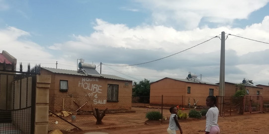 Kleine, staatlich errichtete Wohnhäuser an einer Straße mit Kindern im Stadtteil Lahae in Johannesburg