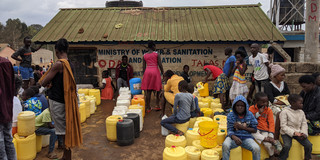 Viele Leute mit Wassercontainern, die vor einem neu errichteden Wasserkiosk im Stadtteil Kibera in Nairobi warten