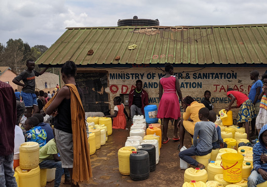 Viele Leute mit Wassercontainern, die vor einem neu errichteden Wasserkiosk im Stadtteil Kibera in Nairobi warten