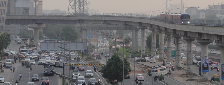Foto einer großen Straße mit überirdischer Metro in einem Vorort von Delhi in Indien
