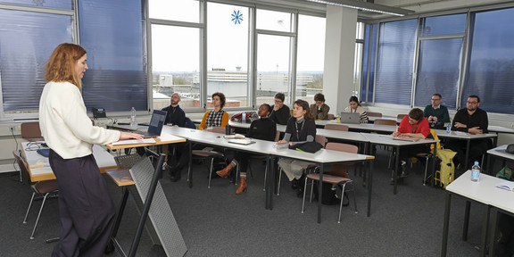 Room with people listening to a person presenting the ICOLMA research project