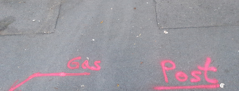 Rote Markierungen mit den Worten Post und Strom auf einem Bürgersteig im Union Viertel in Dortmund