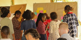 People sticking notes on a pinboard at the UTA-Do Africa Cities Workshop