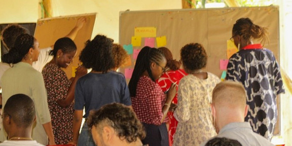 People sticking notes on a pinboard at the UTA-Do Africa Cities Workshop